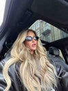 vrouw in auto met zonnebril en lang golvend blond haar