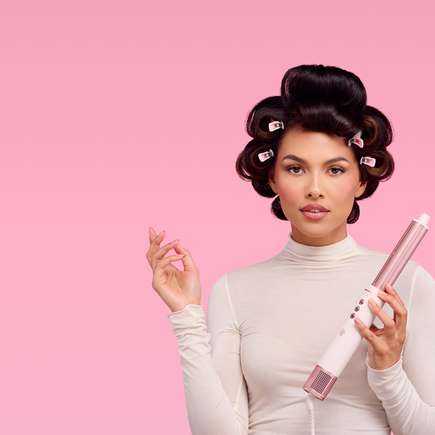 vrouw met watergolf houdt roze airstyler vast tegen roze achtergrond